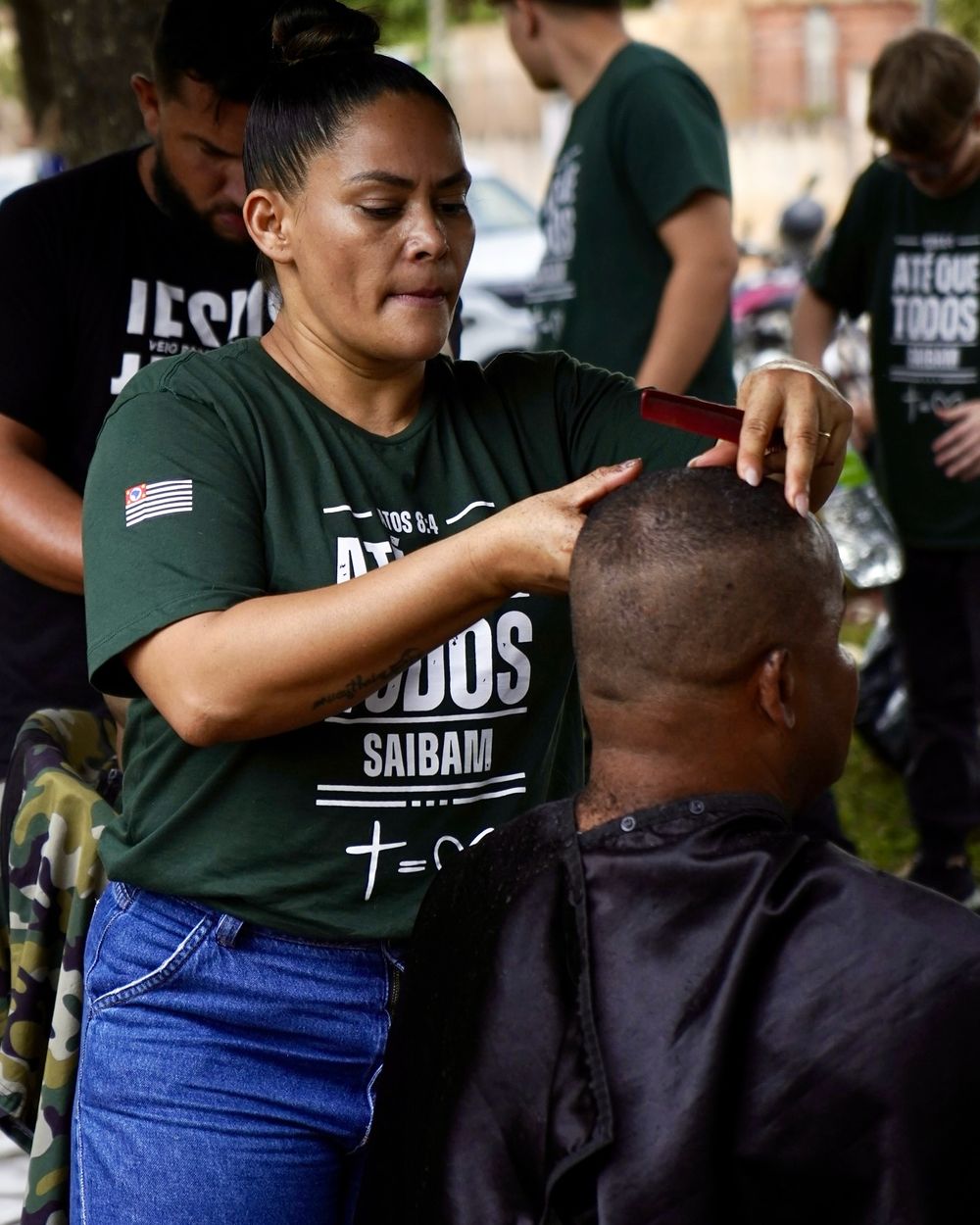 Voluntária da UNEC Paulista cortando o cabelo de um morador durante uma ação social