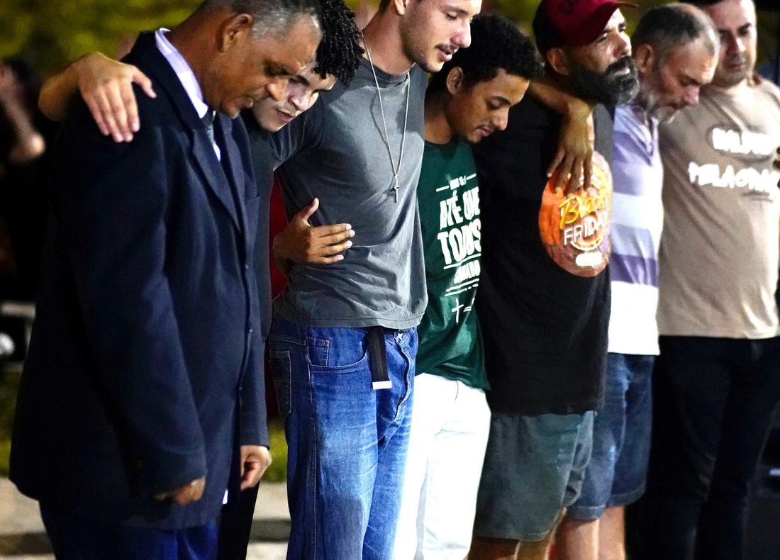 Fileira de homens de braços dados, com a cabeça baixa, em oração durante o avanço em Campinas